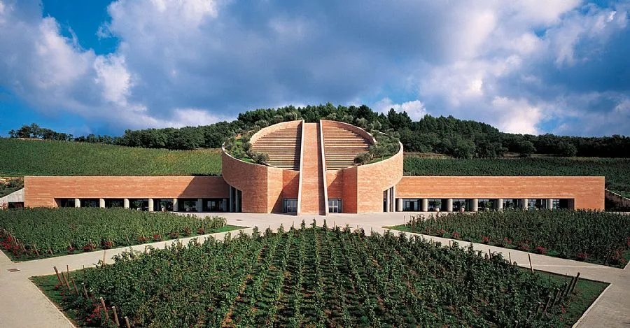 Vista frontale della Cantina Petra a Suvereto: l'edificio in Pietra di Prun progettato dall'architetto Mario Botta, con il cilindro centrale e i vigneti di San Lorenzo in primo piano, Val di Cornia, Toscana
