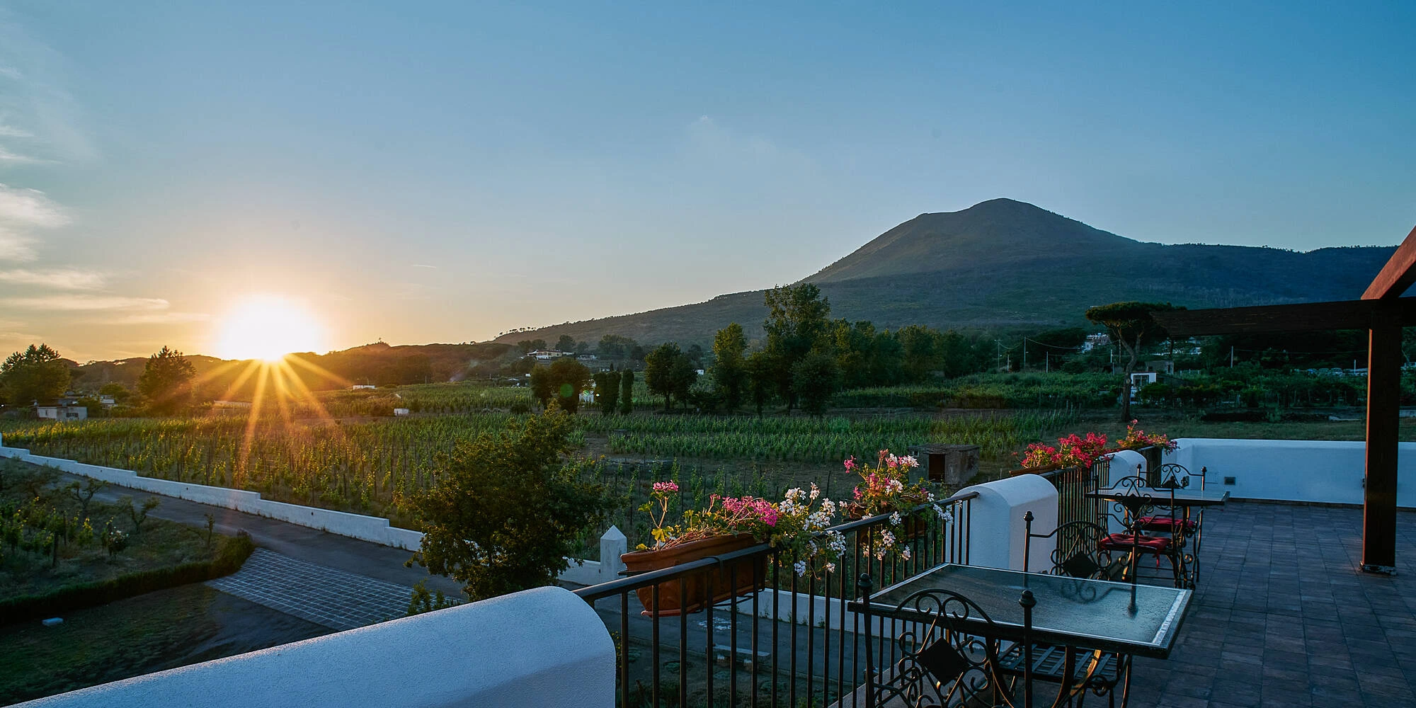 Terrazza panoramica della Cantina del Vesuvio al tramonto, con vista sui vigneti e il cono del Vesuvio sullo sfondo